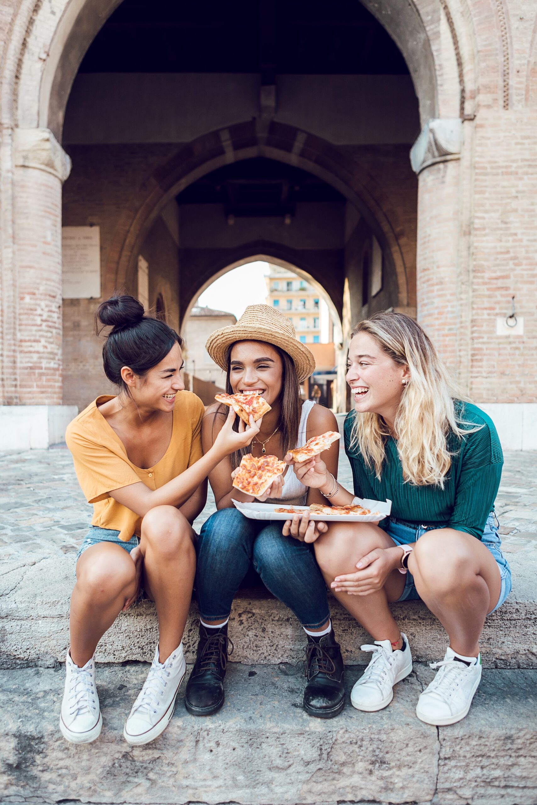 Vertical,Shot,Of,Happy,Multiracial,Women,Eating,Pizza,In,City